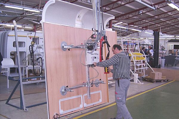 Man operates vacuum lifter vertically to lift a caravan side panel