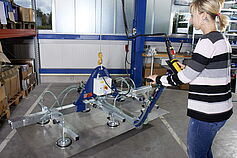 Woman operates vacuum lifter with bendable handle in a production
