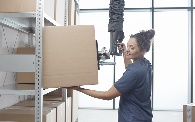 Woman effortlessly operates tube lifter FORCE-LIFT and transports cartons to a shelf